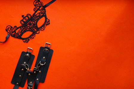 Sexy face mask, handcuffs. Toys for adults. On a white sheet. Sexual pleasures. BDSM. Top view.の写真素材
