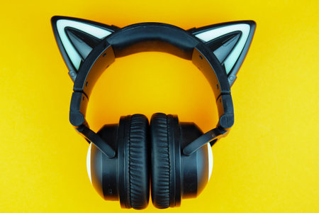 Black wireless headphones isolated on a orange background. A cosplay accessory. Wireless gaming...