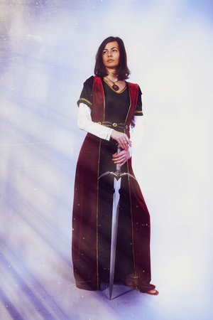 A beautiful young woman posing in historical dress with a sword in her hands