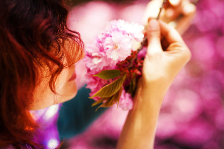 Young woman smelling a beautiful sakura blossom, purple flowers. Spring Magicの写真素材