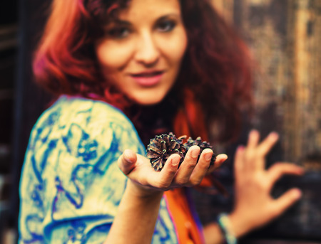 Woman hand holds a fir-cone on wood background, Ecology concept .の写真素材