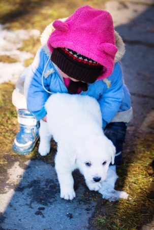 young girl carries a puppy dog in her arms.の写真素材