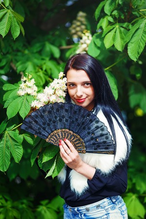 Beautiful Girl with flowers, glamour white fur, posing next to blooming magical spring  flowers. Flower Backgroundの写真素材