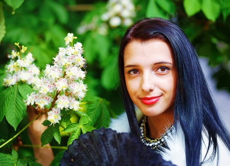 Beautiful Girl with flowers, glamour white fur, posing next to blooming magical spring  flowers. Flower Backgroundの写真素材
