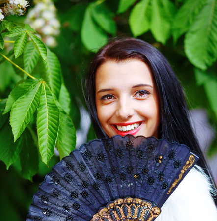 Smiling young woman smelling a beautiful sakura blossom, purple flowers. Spring Magic, and beautiful ornamental fan. Flower backgroundの写真素材