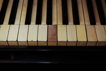 Closeup of black and white piano keys and wood grain with vintage sepia tone one ragged keys.の写真素材
