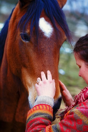 portrait woman and horse in outdoor. woman hugging a horse and  has feather in her hairの写真素材