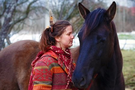 Portrait woman and horse in outdoor. Woman hugging a horse and has feather in her hair.の写真素材