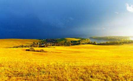 color landscape with storm clouds, green and yellow meadow and lakeの写真素材