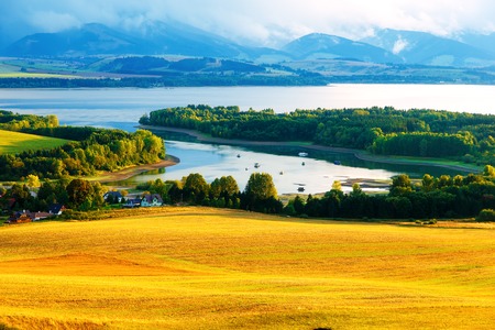 Beautiful landscape, green and yellow meadow and lake with mountain in background. Slovakia, Central Europeの写真素材