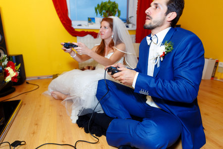 bride and groom playing together videogames with joysticks - gaming and wedding conceptの写真素材