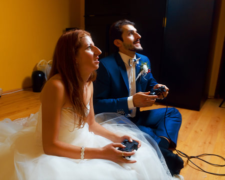 bride and groom playing together videogames with joysticks - gaming and wedding conceptの写真素材