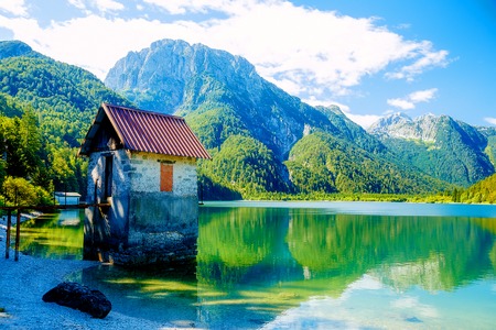 small building at a beautiful lake surrounded by stunning mountain landscapeの写真素材
