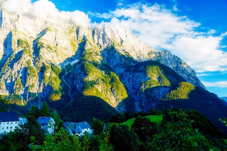 beautiful alpine mountain landscape on summer day with little village in the valley.の写真素材