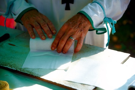 man wrapping wax candle into paper at market palceの写真素材