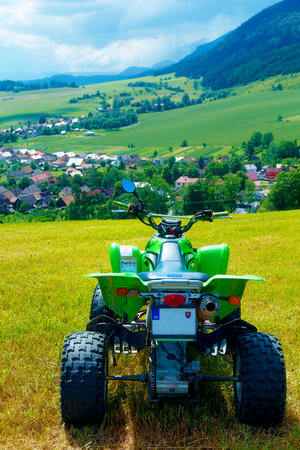 Green Quad in landscape with village in the background.の写真素材