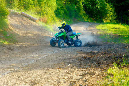 racer with yellow helmet on green quad enjoying his ride outdoors.
