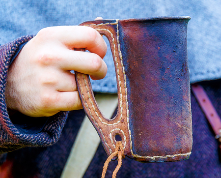 original historic leather cup in detail held by man in middle age dress.の写真素材