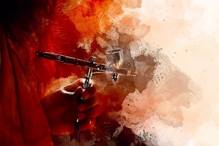 hand holding airbrush gun in painting process and softly blurred watercolor background.の写真素材