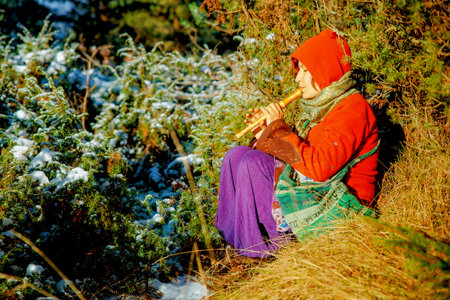 beautiful girl in a historical costume playing her flute in forest.の写真素材