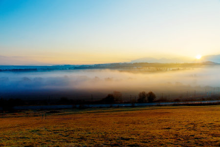 A beautiful morning landscape in fog with road and railway.の写真素材
