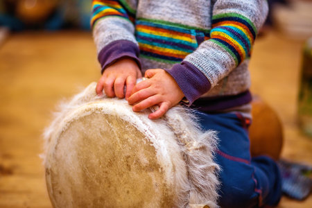 Child playing a djembe drum with natural goat fur features.の写真素材