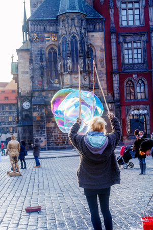 Woman makes big bubbles with rainbow reflection.
