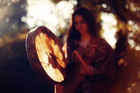 beautiful shamanic girl playing on shaman frame drum in the nature.の写真素材