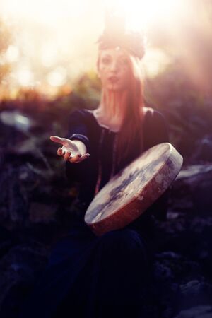 beautiful shamanic girl playing on shaman frame drum in the nature.の写真素材