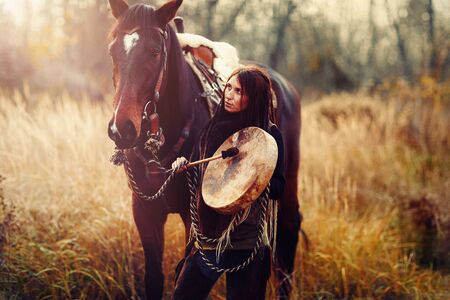 young dreadded girl with her horse and shamanic frame drum.の写真素材