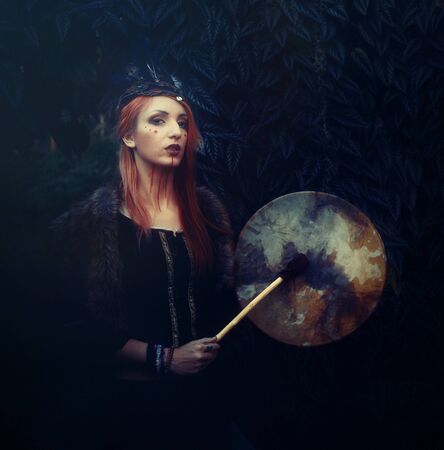 beautiful shamanic girl playing on shaman frame drum in the nature.の写真素材