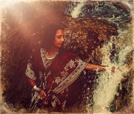 Woman with carafe in beautiful oriental dress in water, old photo effect.の写真素材