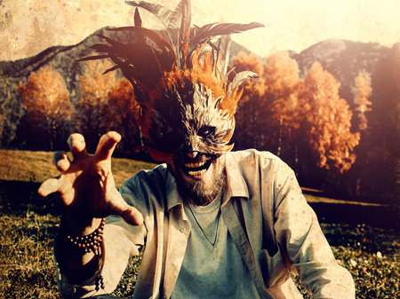 Wild man with a colorful feather face mask.