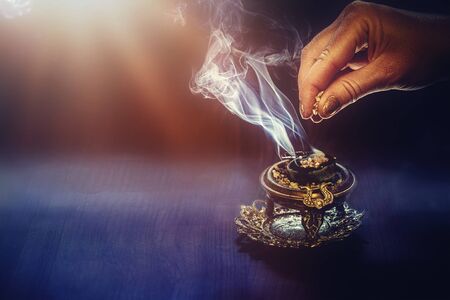 incense in a woman hand, incense smoke on a black background.の写真素材
