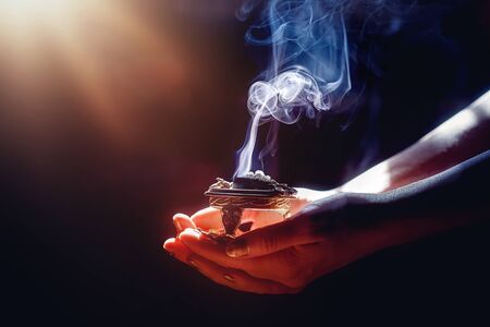 incense in a woman hand, incense smoke on a black backgroundの写真素材
