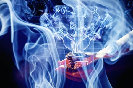 incense in a woman hand, incense smoke on a black backgroundの写真素材
