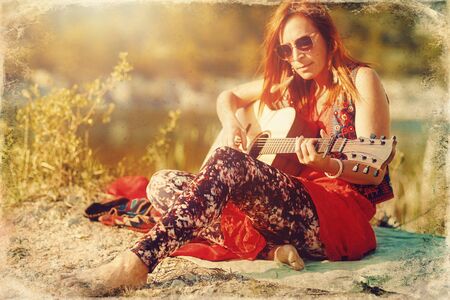 beautiful woman playing with guitar in nature. Old photo effect.の写真素材