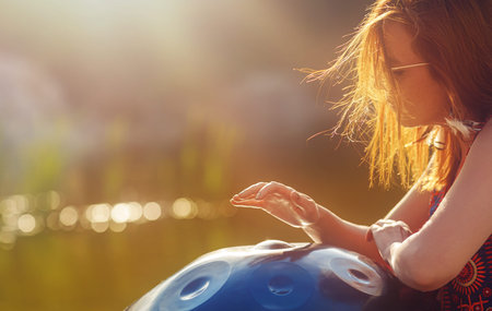 beautiful woman playing with hangdrum in nature.