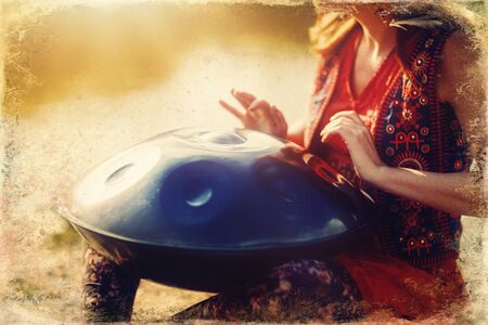 beautiful woman playing with hangdrum in nature. Old photo effect.の写真素材