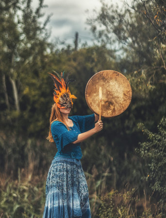 beautiful shamanic girl playing on shaman frame drum in the nature.