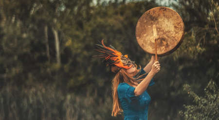 beautiful shamanic girl playing on shaman frame drum in the nature.の写真素材
