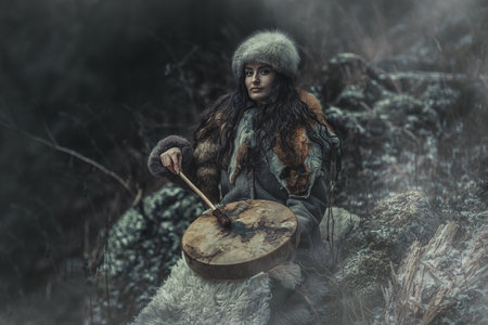 beautiful shamanic girl playing on shaman frame drum in the nature.の写真素材