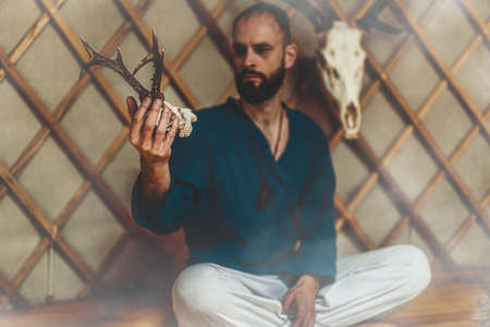 beautiful shamanic man with deer skull in yurt.の写真素材