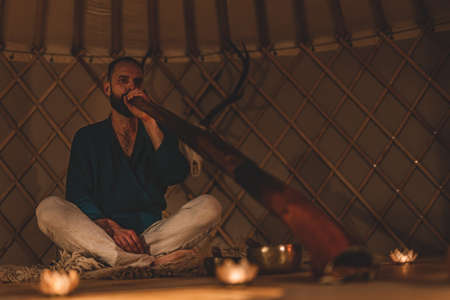 Man playng on didgeridoo by candlelight and tibetian bowl.の写真素材