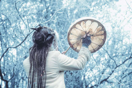 beautiful shamanic girl playing on shaman frame drum in the nature.の写真素材