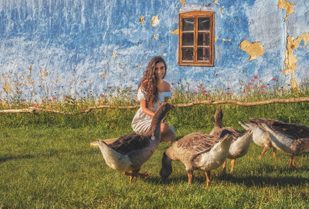 Beautiful exotic woman with a goose on the farm.の写真素材