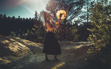 beautiful shamanic girl playing on shaman frame drum in the nature.の写真素材