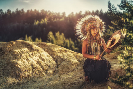 beautiful shamanic girl playing on shaman frame drum in the nature.