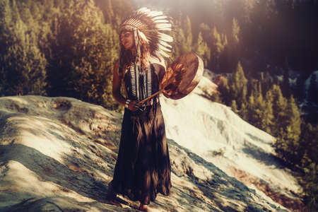 beautiful shamanic girl playing on shaman frame drum in the nature.の写真素材