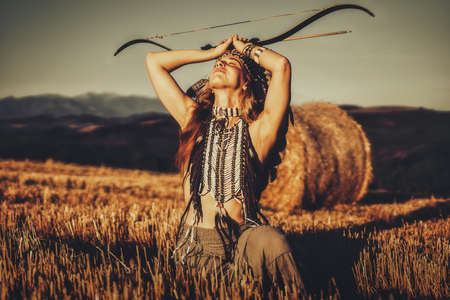 beautiful shamanic girl in the nature with a bow.の写真素材